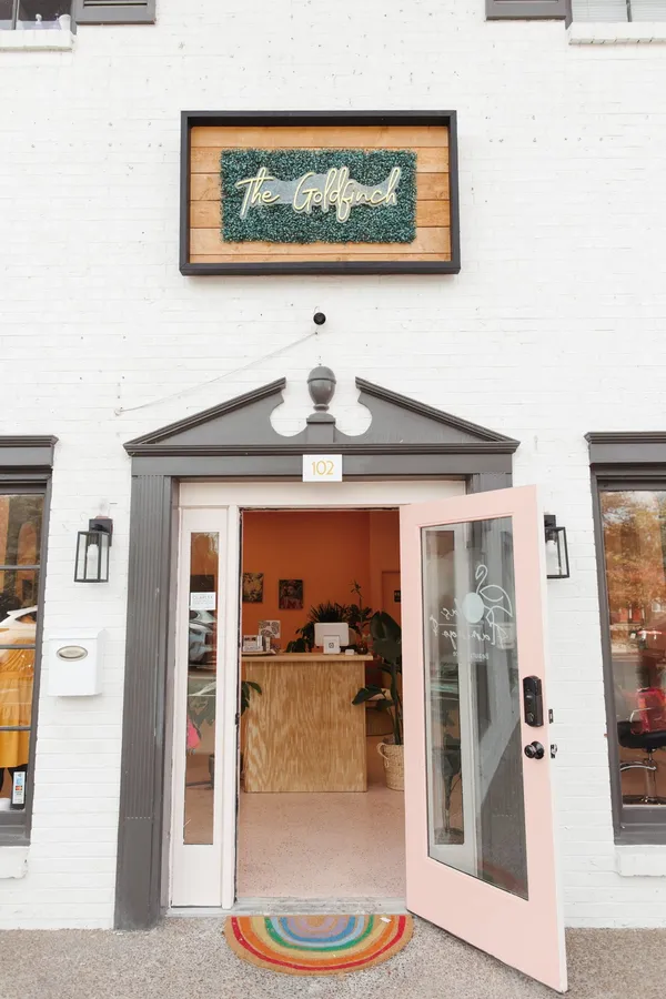 The goldfinch entrance: a pink door in a white brick building