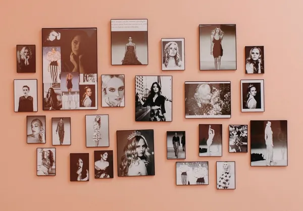 A wall of black-and-white beauty and runway photos on the salon pink wall